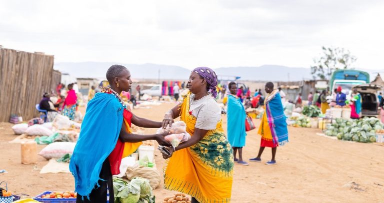 Two women trading fresh produce at a local market, showcasing economic independence.